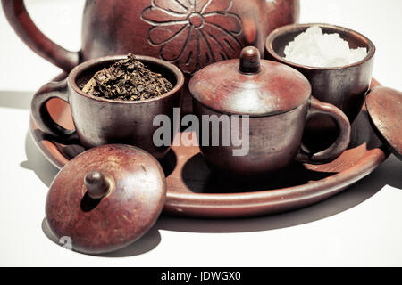 Poci pot or traditional Indonesian tea pot with ingredients of dried tea leaves, rock sugar in beautiful clay cups on presentation earthenware display Stock Photo