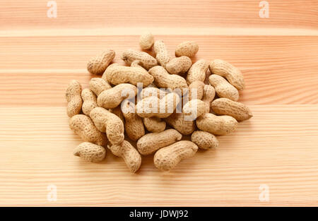 Heap of monkey nuts, peanuts or groundnuts in shells on a wood grain background Stock Photo