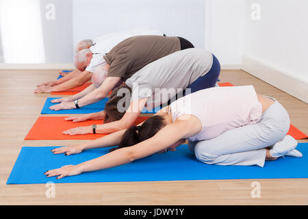 Row of people performing yoga on exercise mats at gym Stock Photo