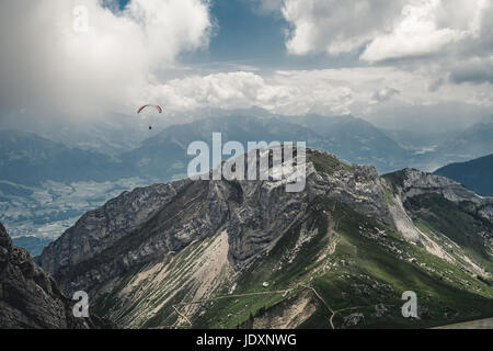 'Souring Above the Mountains' I captured this shot of a paraglider, flying above the mountains, while hiking Mt. Pilatus above Lake Luzerne. Stock Photo