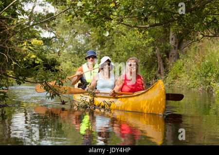 Three people in a canoe, canoeing on the river Lodden, Oxfordshire England UK Stock Photo