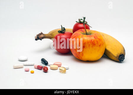 verschiedene bunte Tabletten, Apfel, Banane und Tomaten, isoliert