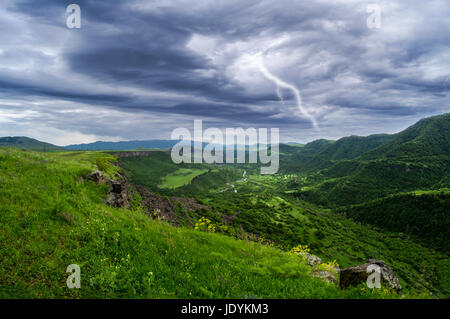 lightning storm clouds landscape in meadow summer day with mountain on horizon Stock Photo