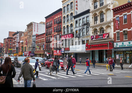NEW YORK CITY - OCTOBER 02, 2016: Pedestrian walking in a crosswalk on the corner of Bowery and Cheste Street in Chinatown Stock Photo