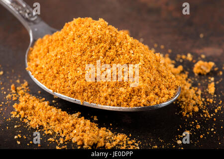 Spoon filled with spices for the preparation of roast on rusty background Stock Photo