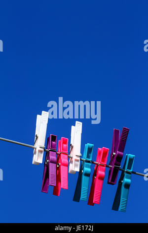 colourful plastic clothes pegs on a washing line on a warm sunny spring day Stock Photo