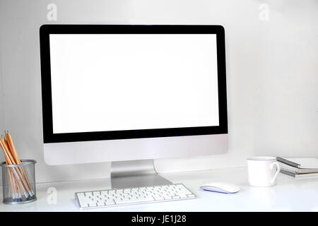 Creative hipster desktop with blank white computer screen, coffee cup and other items on white brick background. Mock up workspace. Stock Photo