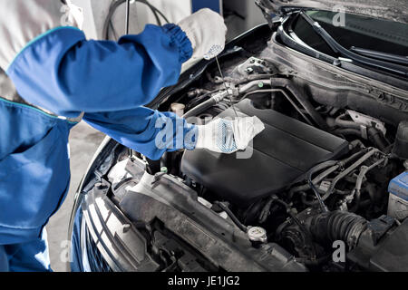 Mechanic checking oil level in a car workshop Stock Photo