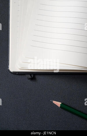 Opened business notepad with white sheets and pencil on the black desk Stock Photo