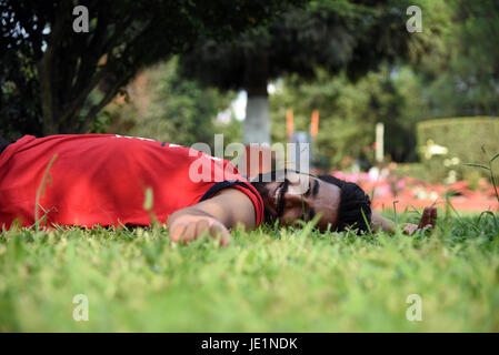 young Nepalese man smiles and poses for photograph lying at the ground Stock Photo