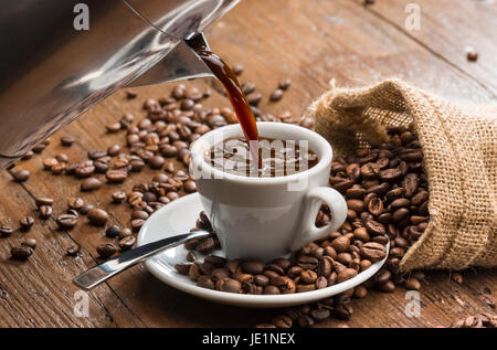 pouring coffee from coffee pot into white coffee cup. Stock Photo