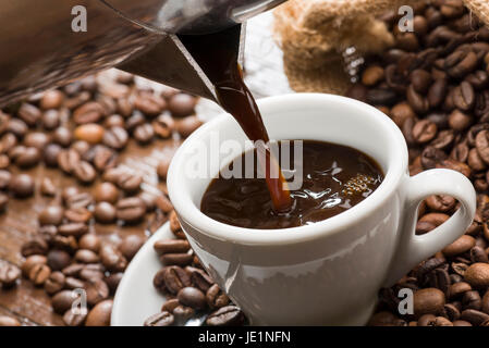 pouring coffee from coffeepot into white coffee cup, closeup. Stock Photo