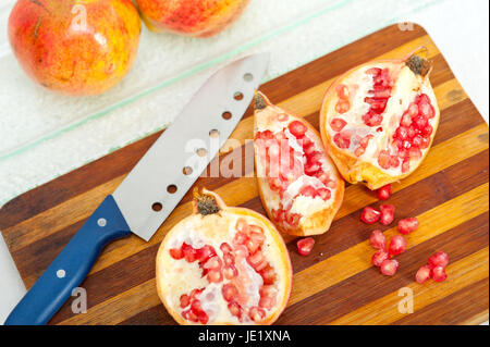 fresh pomegranate fruit over wood cutting board with knife Stock Photo
