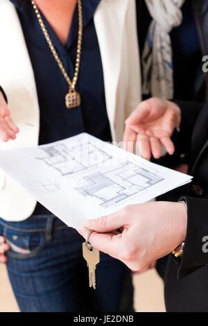 Young realtor explain ground plan to couple in an apartment Stock Photo