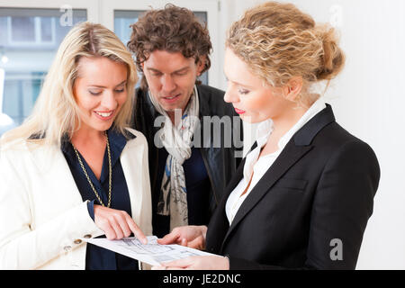 Young realtor explain ground plan to couple in an apartment Stock Photo
