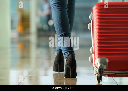 Traveler woman legs walking carrying a suitcase in an airport Stock Photo