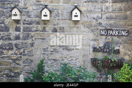 Three wooden Bird boxes and a no parking sign on stone walling Stock Photo