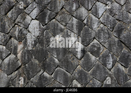 Ancient stone block wall built in a diagonal pattern, from gray stone, stained with soot, in Ashigawa village in Japan: would make good background. Stock Photo