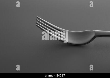 Close-up shot of metallic fork lying down on dark gray surface. Minimalistic design photo. Stock Photo