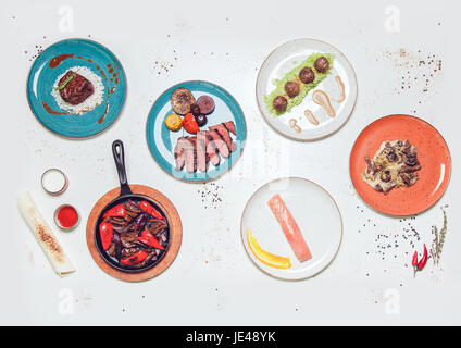 Plates with dishes of meat and fish on a white table. view from above. Stock Photo