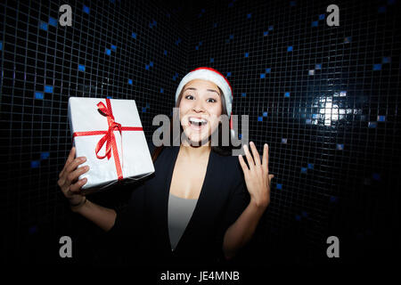 Ecstatic businesswoman in Santa cap holding Christmas present Stock Photo