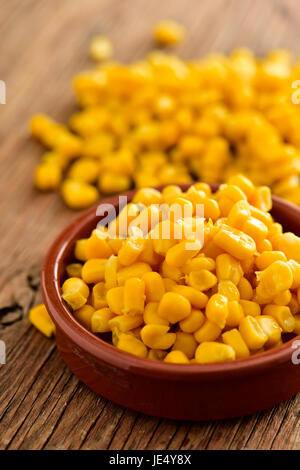 closeup of an earthenware bowl full of sweet corn on a rustic wooden surface Stock Photo