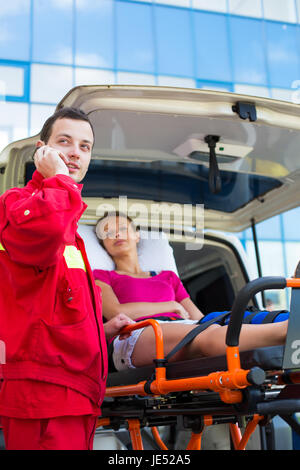 Paramedic taking care of a female patient - calling a hospital