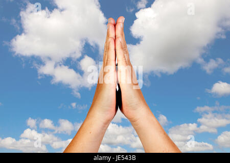 Hands in prayer position against a beautiful sky background