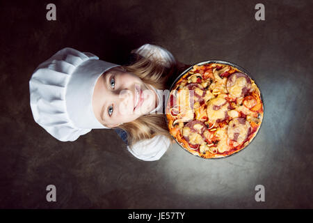 elevated view of little girl holding pizza and looking at camera Stock Photo