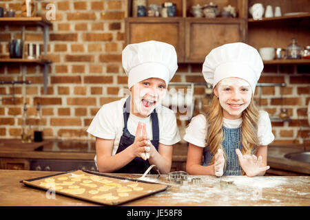 little boy and girl playing with flour while making shaped cookies Stock Photo