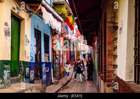 Bogota, Colombia -  Local Colombian people are seen walking down the colourful, narrow Calle del Embudo in the historic La Candelaria district. Stock Photo