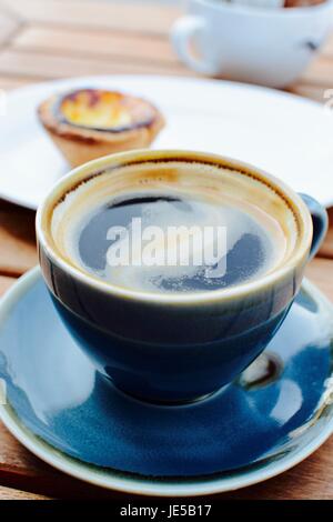 Black coffee with a Portuguese tart in the background Stock Photo