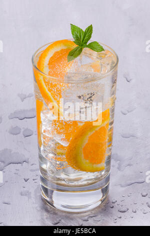 Glass of refreshing cold mineral water with pieces of orange Stock Photo