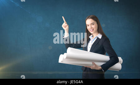 Building, developing, consrtuction and architecture concept - smiling beautiful businesswoman in suit with blueprint Stock Photo