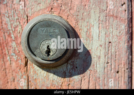 Tarnished Yale rim and cylinder mounted to rotting garage door. Stock Photo