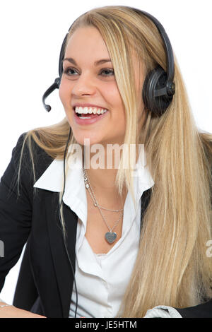 EIne junge attraktive Frau mit einem Headset auf dem Kopf lacht während sie telefoniert. Stock Photo