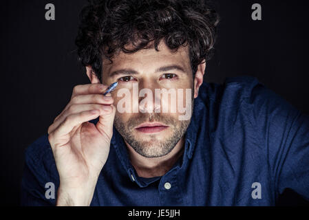 Man squinting at camera and pointing with pen Stock Photo
