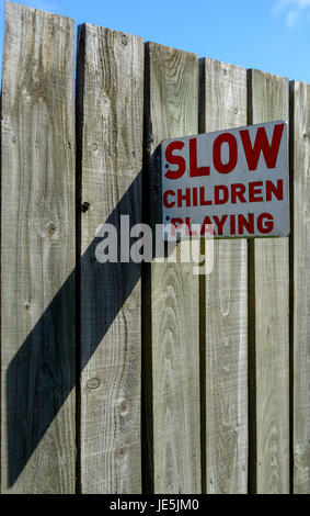 'Slow Children Playing ' sign mounted to wooden fence. Stock Photo