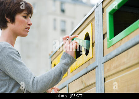 Woman placing plastic bottle in recycling bin Stock Photo