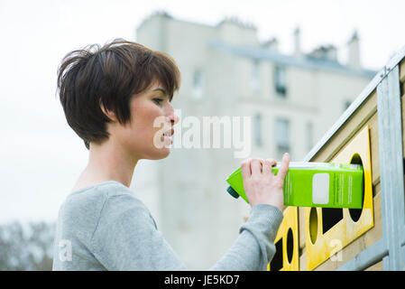Woman placing carton in recycling bin Stock Photo