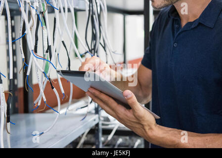 Electrician using digital tablet while inspecting equipment Stock Photo