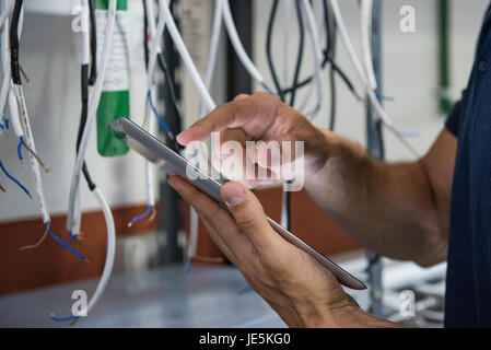 Electrician using digital tablet while inspecting equipment Stock Photo