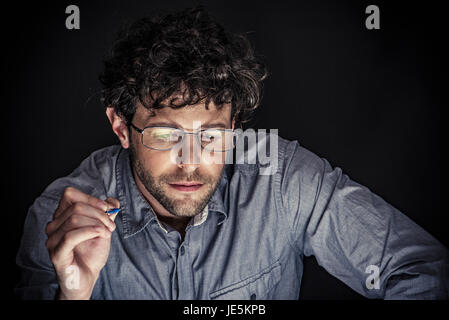 Man holding pen and looking down in concentration Stock Photo