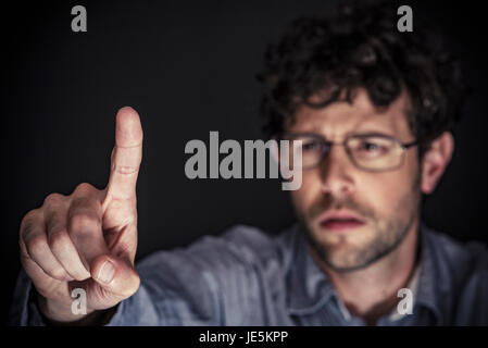 Man using index finger on transparent touch screen Stock Photo