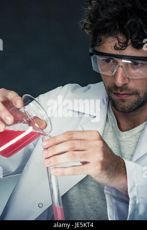 Scientist pouring liquid into test tube Stock Photo