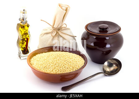 Still life of Millet cereal in ceramic pial, ceramic pot, old spoon and canvas bag for cereals, oil with spices and seasonings, isolated on white back Stock Photo