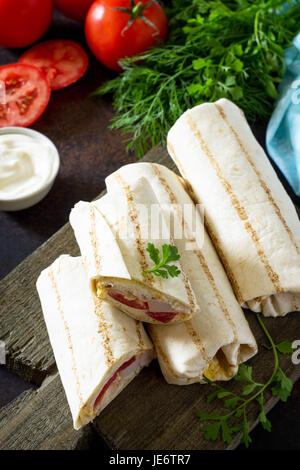 Shawarma pita bread with grilled chicken, fresh vegetables and cream sauce on a background of brown stone. Stock Photo