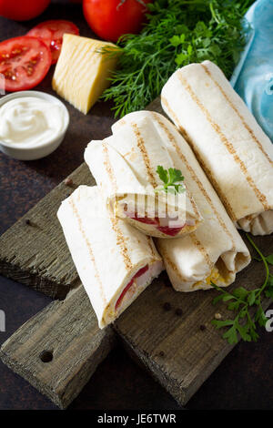 Shawarma pita bread with grilled chicken, fresh vegetables and cream sauce on a background of brown stone. Stock Photo