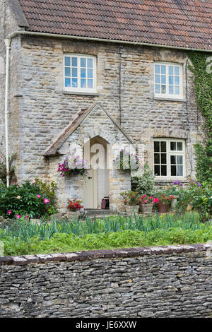 Stone cottage and floral hanging baskets and front garden in Coln St Aldwyns. Cotswolds, Gloucestershire, England Stock Photo