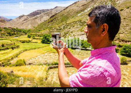 Closeup of a tourist filming and taking photos of a valley in the Atlas mountains. Stock Photo